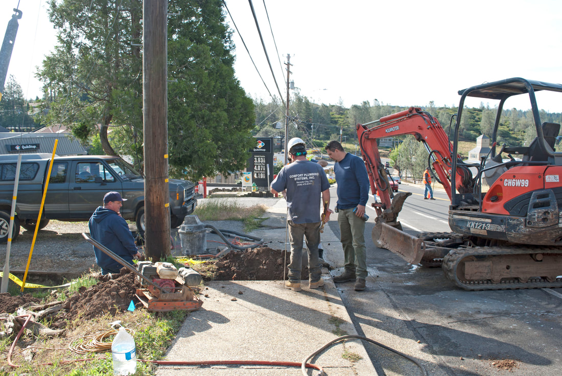 Hooking up  a new home to city sewer system, digging sewer lines on sidewalk and street using tractors and shutting down street Nevada City, CA