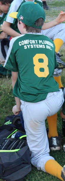 Young boy in baseball uniform with Comfort Plumbing Systems on back of team jersey